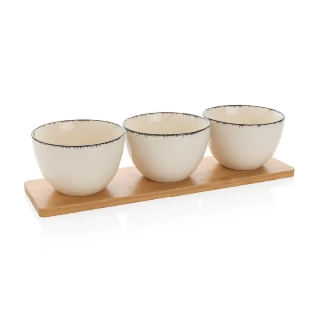 Drie witte keramische kommen met zwarte rand op een bamboe tray