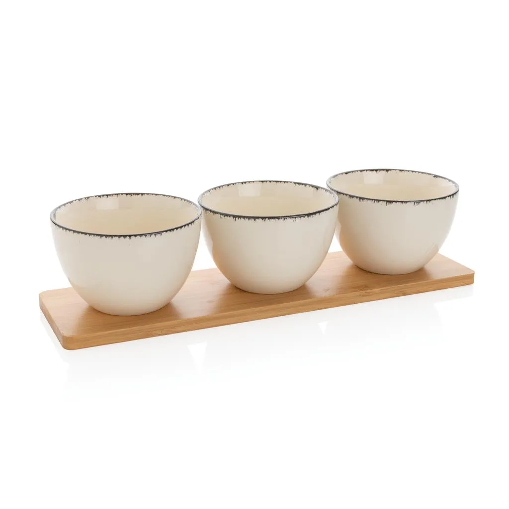 Drie witte keramische kommen met zwarte rand op een bamboe tray
